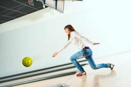 pleasant young woman throws a bowling ball, looks at the target and smilingの写真素材