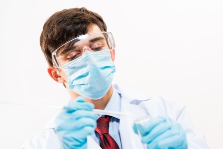 scientist working in the lab, in protective mask, examines a test tube with liquidの写真素材