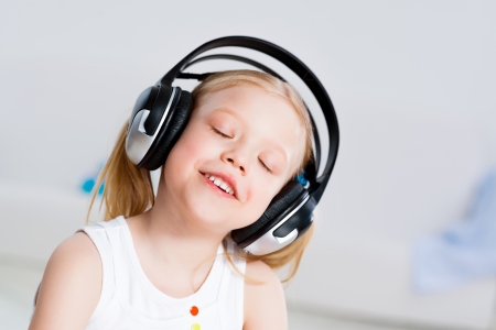 Pretty girl listening to music with headphones lying on the floor in the living roomの写真素材