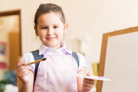 Portrait of Asian girl in apron interested in painting at an art schoolの写真素材