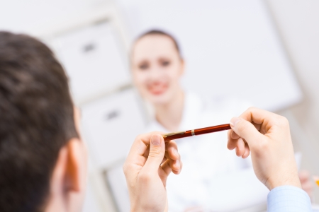 close-up, hands holding pen, interviewing, background bright young lady smilingの写真素材