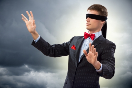 young blindfolded man  his arms and looking for a way outの写真素材