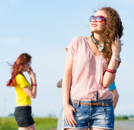 young woman with headphones on a background of blue sky and funny friendsの写真素材