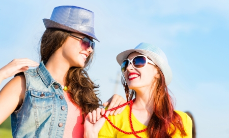 Two young girlfriends having fun on the background of blue sky and friendsの写真素材