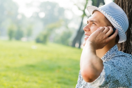 young man in a summer park on the grass with cell phoneの写真素材