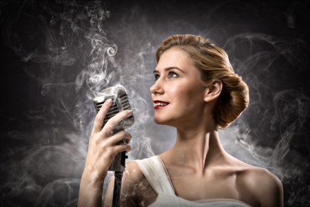 beautiful blonde woman singer with a microphone, eyes opened, around smokeの写真素材