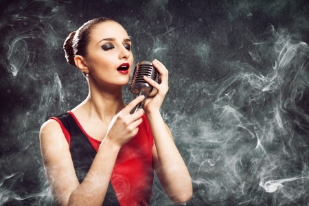 beautiful blonde woman singer with a microphone, eyes closed, around smokeの写真素材