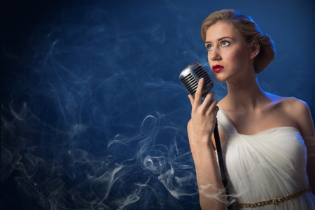 attractive female singer with a microphone behind her abstract backgroundの写真素材