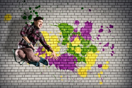 young male dancer jumping behind a wall covered in paintの写真素材