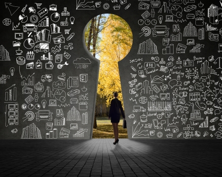 businesswoman standing at the exit, autumn forest through a hole in the wallの写真素材