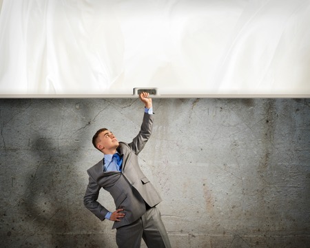 image of a businessman holding a banner with one hand, place for textの写真素材