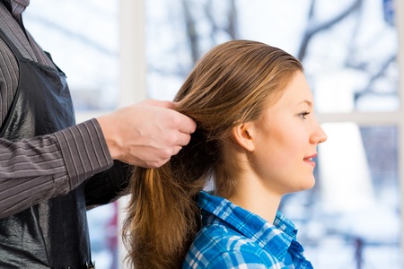 male hairdresser puts woman s hair in a hairdressing salonの写真素材