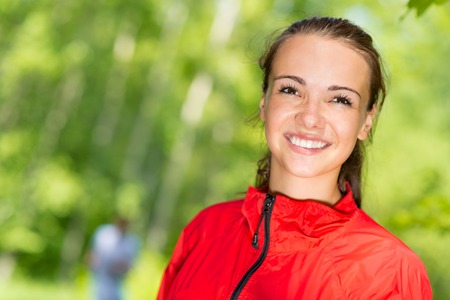 healthy young female athlete running in a summer park smiling and happy while working outの写真素材