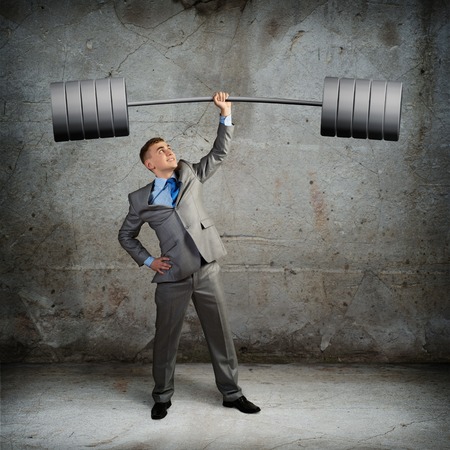 businessman holding a barbell with one hand, the concept of achievements in businessの写真素材