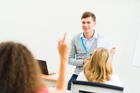 young teacher man talking with students in the classroomの写真素材