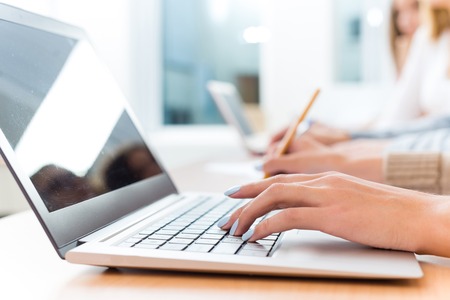 close-up of female hands on the laptop keyboard, students listen to the teacher at the University ofの写真素材