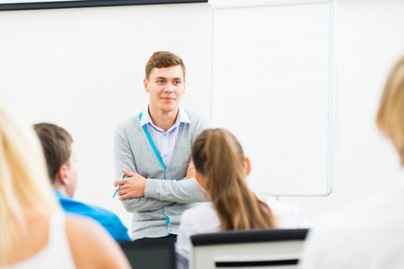 young teacher man talking with students in the classroomの写真素材