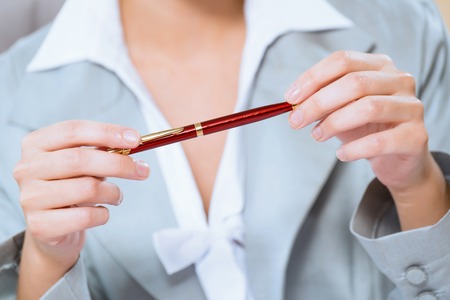 close-up of hands of a business woman, holding a red penの写真素材