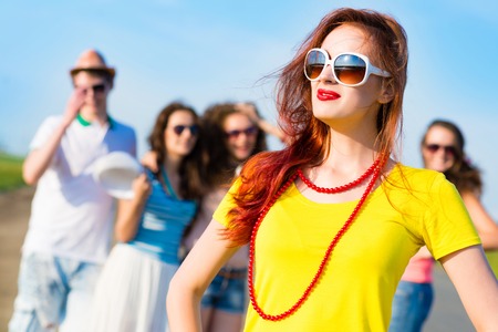 stylish young woman in sunglasses on the background of blue sky and friendsの写真素材