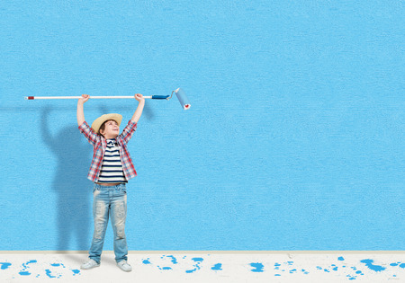 image of a boy with hat standing near the painted wallの写真素材