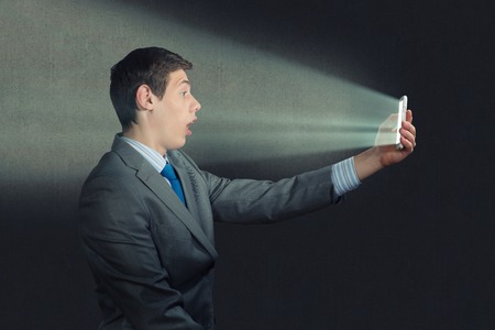 businessman with a cell phone, the light falls on the face of the screenの写真素材