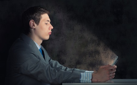 businessman with a tablet computer, the light falls on the face of the screenの写真素材