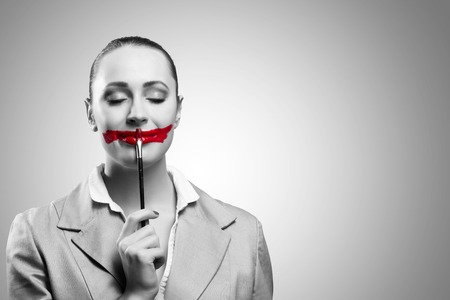 Conceptual black and white image of a young woman with vivid red mouthの写真素材