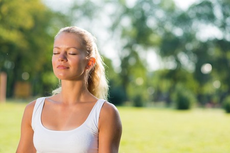young attractive woman of exercises on the grass in the parkの写真素材