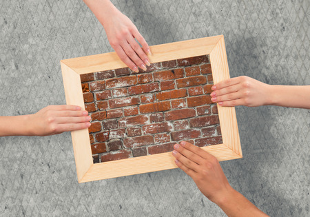 Close up of human hands holding wooden frame with brick textureの写真素材