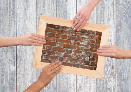 Close up of human hands holding wooden frame with brick textureの写真素材