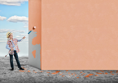 Cute little girl with paint roller in handの写真素材