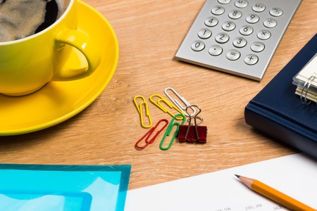 image of a cup of coffee, calculator, notepad and pencil  business still life
