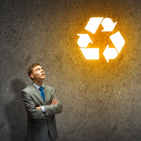 Young businessman looking at recycle symbol above headの写真素材