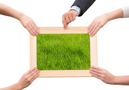 Close up of human hands holding wooden frame with green grass