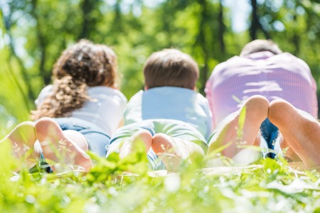 Young happy family lying in park barefootの写真素材