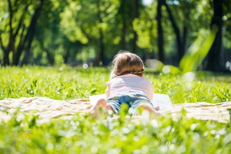 Rear view of little girl lying in summer parkの写真素材