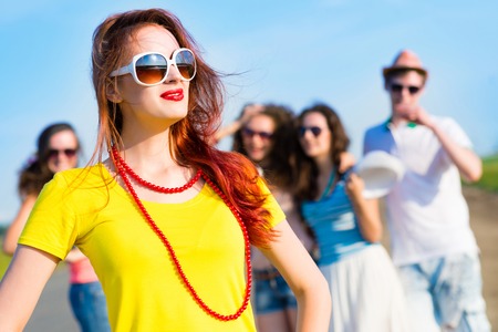 stylish young woman in sunglasses on the background of blue sky and friendsの写真素材