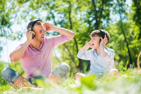 Father and kid in summer park enjoying musicの写真素材