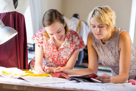 Two young pretty needlewomen in studio working at orderの写真素材