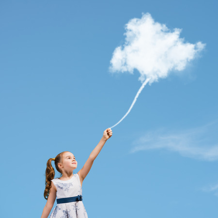 Cute girl in dress holding cloud on ropeの写真素材