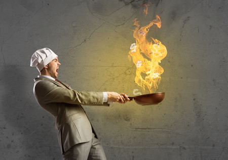 Young man in business suit and cook hat holding panの写真素材