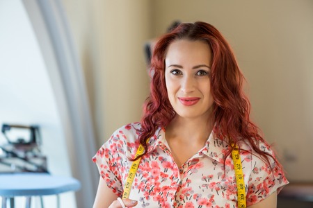 Young pretty needlewoman cutting fabric with scissorsの写真素材