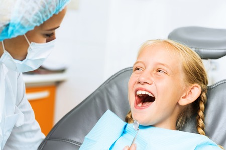 Little cute girl sitting in chair at dentistの写真素材