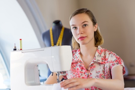 Young attractive needlewoman at studio working with sewing machineの写真素材