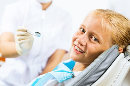 Little cute girl sitting in chair at dentistの写真素材