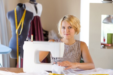Young attractive needlewoman at studio working with sewing machineの写真素材