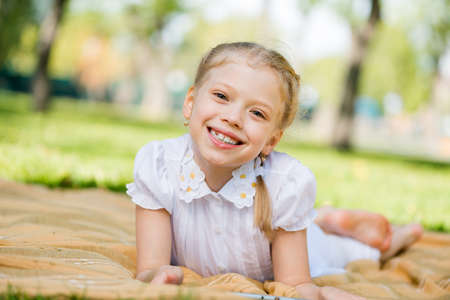 Little cute girl lying in park and using tablet pcの写真素材