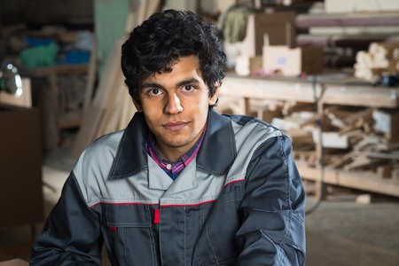 Young craftsman in uniform working at carpentryの写真素材