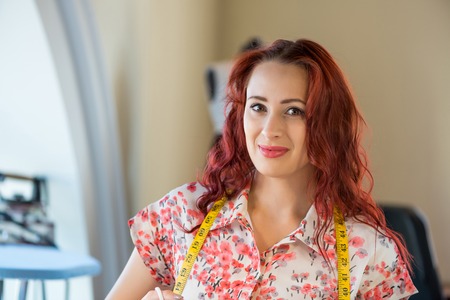 Young pretty needlewoman cutting fabric with scissorsの写真素材