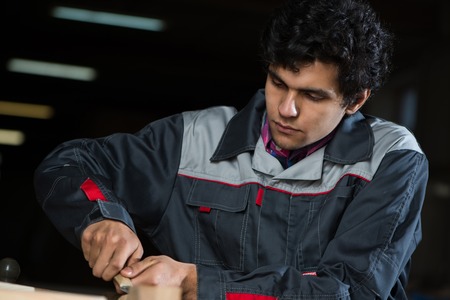 Young craftsman in uniform working at carpentryの写真素材